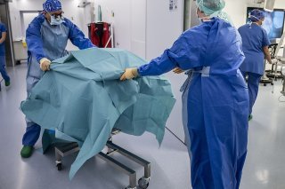Thierry Berney (gauche), médecin-chef du service de transplantation des HUG, déplace un rein dans un autre bloc où attend un malade (archives 2022). KEYSTONE/MARTIAL TREZZINI